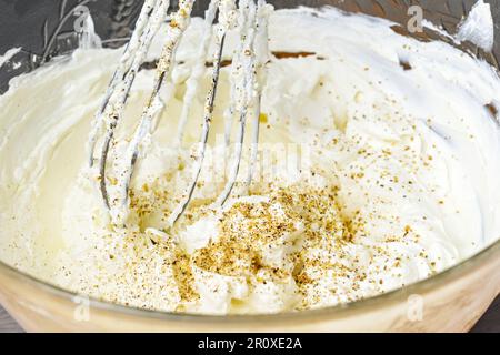 Le fouet mélange une généreuse trempette de fromage de chèvre à la crème avec des noix moulées et du poivre dans un bol en verre, une concentration sélectionnée, une profondeur de champ étroite Banque D'Images