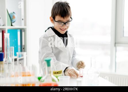 Garçon d'école portant des lunettes de protection faisant une expérience de chimie en classe de sciences élémentaires.Pupille avec tubes d'équipement en laboratoire Banque D'Images