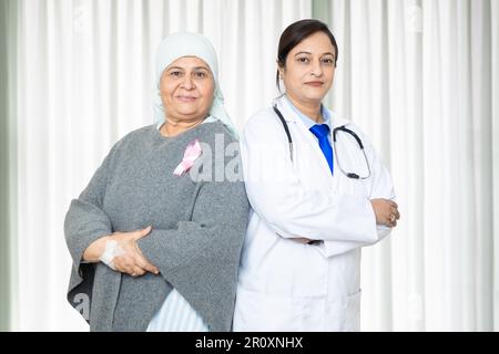 Portrait de femme aînée indienne cancer patient et docteur font debout des bras croisés à l'hôpital, concept de soins de santé. Banque D'Images