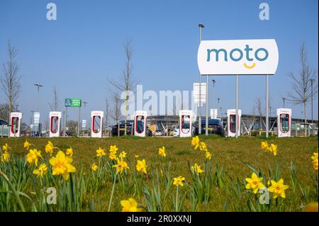 Les voitures Tesla se chargent à des superchargeurs Tesla dans une station-service d'autoroute en Angleterre. Banque D'Images