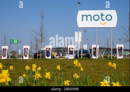 Les voitures Tesla se chargent à des superchargeurs Tesla dans une station-service d'autoroute en Angleterre. Banque D'Images