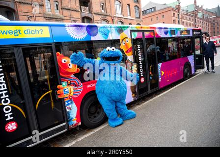 Hambourg, Allemagne. 10th mai 2023. Une personne habillée comme un biscuit monstre se tient devant un bus de chemin de fer élevé de Hambourg, qui est décoré avec les personnages Ernie (l) et Bert à l'occasion du 50th anniversaire de Sesame Street. Credit: Daniel Bockwoldt/dpa/Alay Live News Banque D'Images