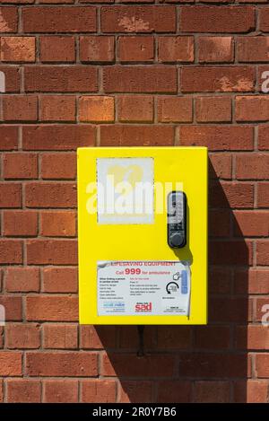 Défibrillateur monté sur un mur de briques dans une boîte jaune vif Banque D'Images