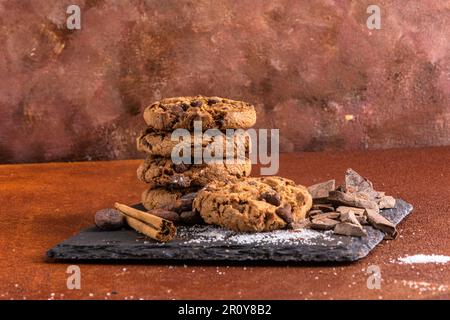 Petite pile de biscuits avec des copeaux de chocolat. Studio photo dans un fond rustique avec une atmosphère chaleureuse un peu rétro. Banque D'Images