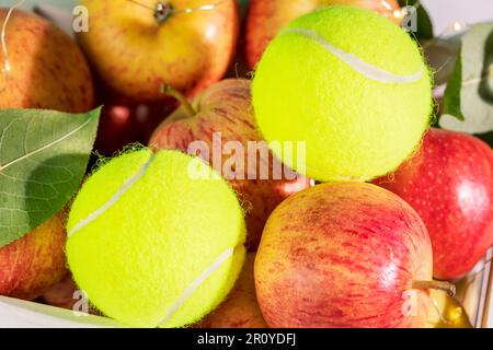 Composition de tennis avec balles de tennis jaunes en gros plan et pommes rouges naturelles Banque D'Images