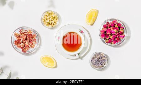 Tasse de thé, fleurs naturelles, herbes et citrons sur fond blanc Banque D'Images