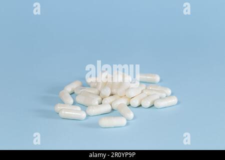 Groupe simple et minimaliste de capsules de médicaments sur fond bleu. Banque D'Images