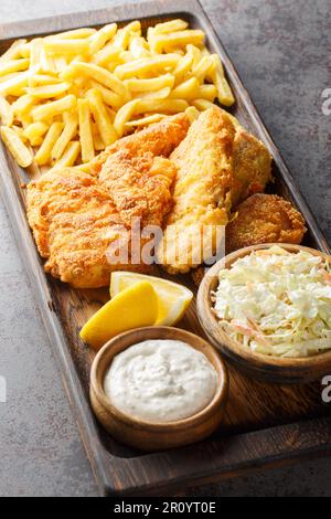 Plats rapides poisson frit pané servi avec de la coleslaw, des frites et de la sauce tartare sur un plateau en bois sur la table. Verticale Banque D'Images