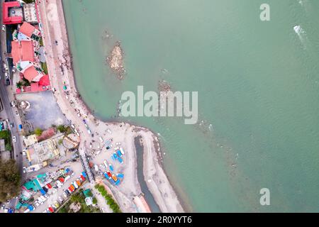 tir de drone aérien montrant des radeaux pour des sports d'aventure sur l'eau sur les eaux bleues du fleuve ganga à rishikesh avec des gens observant les ghats sur le Banque D'Images