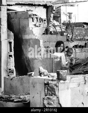 Une fille, tenant un petit enfant, se tient dans les ruines de leur maison de Saigon après une attaque du Viet Cong sur 31 janvier 1968. Banque D'Images