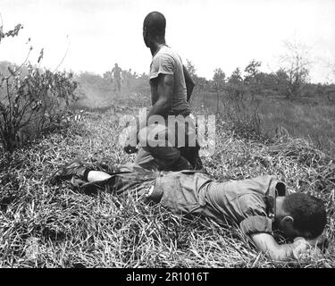 Un jeune lieutenant américain, sa jambe brûlée par un piège à phosphore blanc éclatant de Viet Cong, attend un hélicoptère Medevac alors qu'il est traité par un médic. Vers 1966. Banque D'Images
