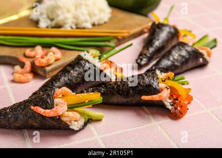 Des cônes de sushis savoureux et des ingrédients sur fond de carreaux de couleur, en gros plan Banque D'Images