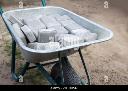 Permet de déconcentrer les carreaux de briques empilés sur une brouette. Briques grises pour la chaussée. Empiler les pavés empilés en piles. Espace de copie gris Banque D'Images