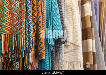 Gros plan de carreaux multicolores, étoles accrochées en rangée dans le magasin, articles saisonniers confortables. Concept de shopping d'hiver d'automne Banque D'Images