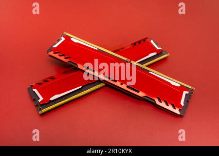 ddr4 cartes mémoire ram avec dissipateurs thermiques en aluminium rouge sur une surface de couleur assortie disposées en forme de x. Banque D'Images