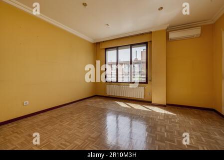 Séjour vide avec parquet en chêne, radiateurs en aluminium blanc sous une longue fenêtre en aluminium sombre avec vue Banque D'Images