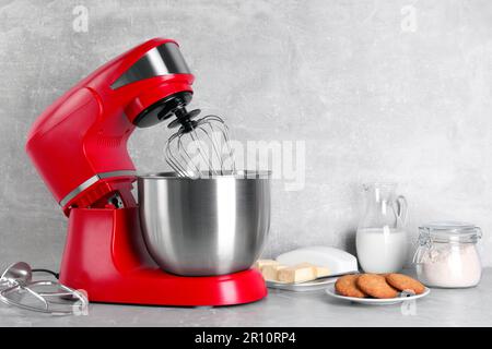 Batteur rouge moderne, biscuits et ingrédients sur table en marbre gris clair. Espace pour le texte Banque D'Images