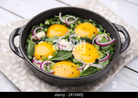 Savoureux Shakshouka dans une poêle sur table en bois blanc, gros plan Banque D'Images