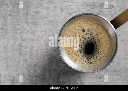 Cafetière turque avec boisson chaude sur table grise, vue de dessus. Espace pour le texte Banque D'Images