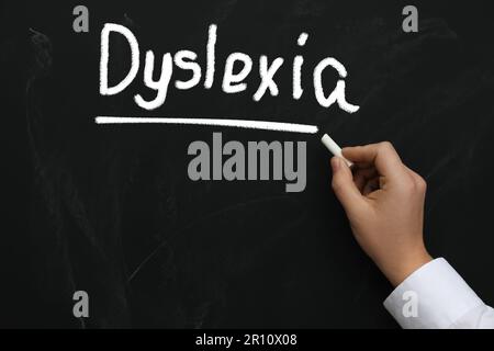 Homme écrivant le mot Dyslexie sur le tableau noir, gros plan Banque D'Images