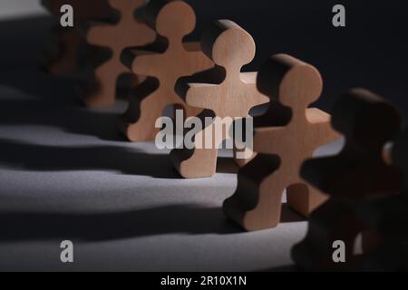 Concept de recrutement et d'embauche. Figure en bois humain dans le faisceau de lumière entre autres sur la table, gros plan Banque D'Images