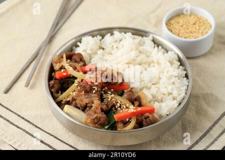 Bœuf de Corée Bulgogi avec légumes sautés sur riz blanc, servi sur un bol en acier inoxydable Banque D'Images