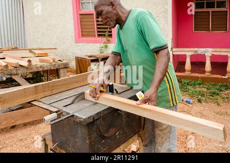 Un charpentier utilise une scie électrique pour couper l'extrémité d'un morceau de bois. Banque D'Images