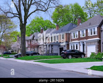 Rue de banlieue avec arbres matures et grandes maisons de deux étages Banque D'Images