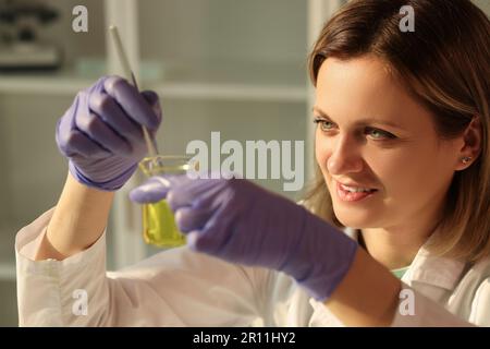 Femme scientifique souriante tenant un flacon de liquide jaune Banque D'Images