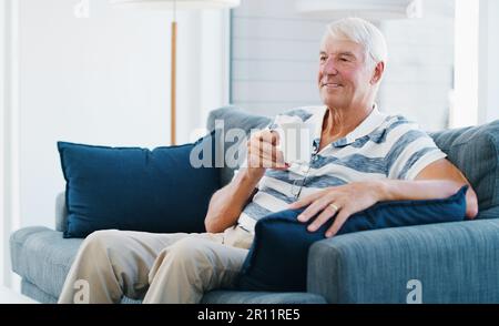 Tellement de bons souvenirs à raconter. un homme âgé se détendant avec une tasse de café sur le canapé à la maison. Banque D'Images