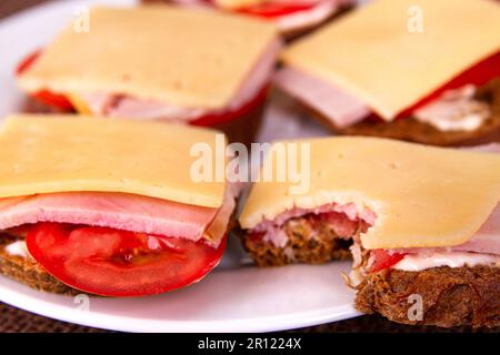 Piquer le sandwich sur l'assiette blanche avec d'autres sandwichs faits soi-même. Vue latérale. Gros plan. Mise au point sélective Banque D'Images