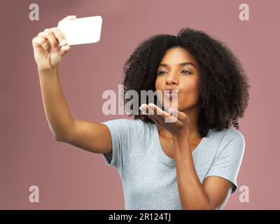 Theres toujours le temps pour un autre selfie. Photo en studio d'une jeune femme attirante prenant un selfie sur fond rose. Banque D'Images