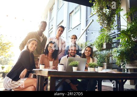 Nous préférons nos réunions dans un cadre détendu. Portrait rogné d'une équipe de collègues utilisant un ordinateur portable pendant une réunion dans un café extérieur. Banque D'Images