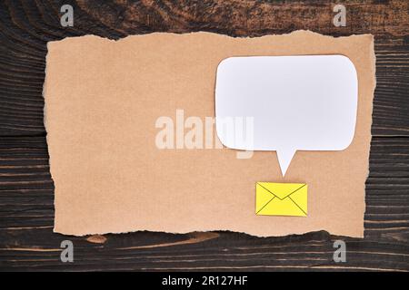 Papier artisanal déchiré avec icône d'e-mail et bulle de discours vierge, style d'art en papier. Carte de vœux, lettre, maquette d'invitation. Flat lay, vue de dessus, co Banque D'Images