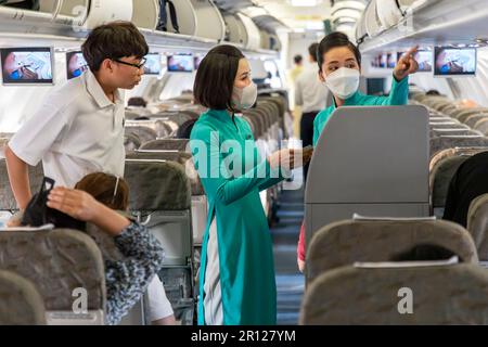 L'équipage de cabine de Vietnam Airlines porte l'uniforme AO dai traditionnel en vol Banque D'Images