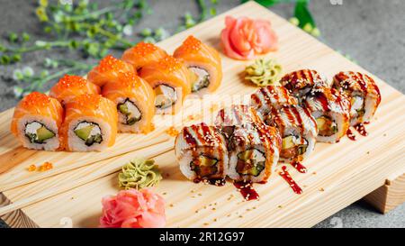 Une variété de petits pains à sushi disposés soigneusement sur une planche à découper en bois, accentuée par une fleur unique au centre Banque D'Images