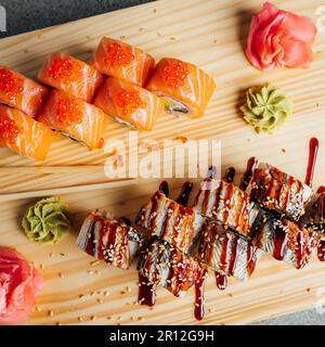 Une variété de petits pains à sushis fraîchement préparés, y compris du sashimi, disposés sur un panneau de bois rustique, prêts à être dégustés Banque D'Images