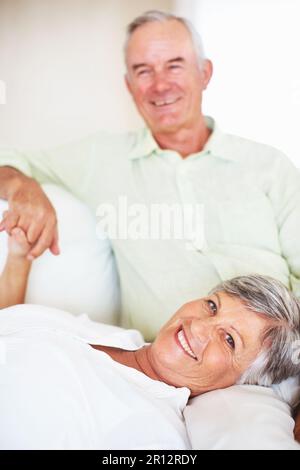 Couple d'âge mûr affectueux ensemble. Portrait d'une femme aimante couché sur un homme à la maison. Banque D'Images