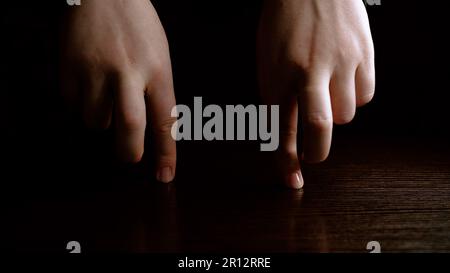 Les doigts de sexe masculin dansent sur un fond sombre. Concept amusant et théâtral. Banque D'Images