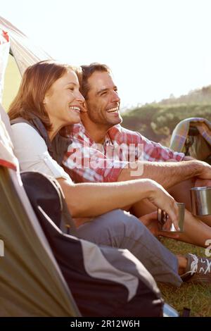Ils se sentent si libres dans la nature. Un jeune couple qui profite de l'extérieur lors d'un voyage en camping. Banque D'Images