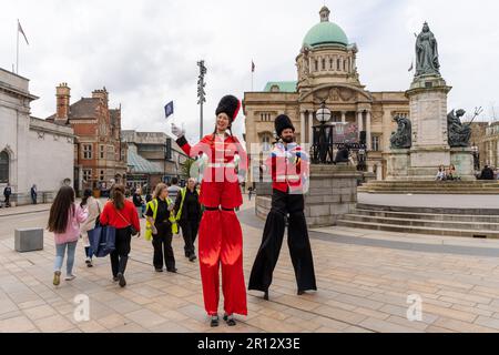 Les marcheurs à pilotis vêtus de costumes militaires habillés de fantaisie accueillent les gens à Kingston upon Hull, au Royaume-Uni, le jour du couronnement du roi Charles III Banque D'Images