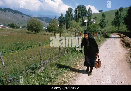 Brasov Comté, Roumanie, environ 1999. Une veuve marchant sur la voie du village dans la campagne. Banque D'Images