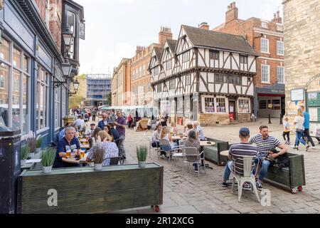 Les personnes qui mangent et boivent aux tables de plein air dans la ville historique de Lincoln, au Royaume-Uni. Banque D'Images