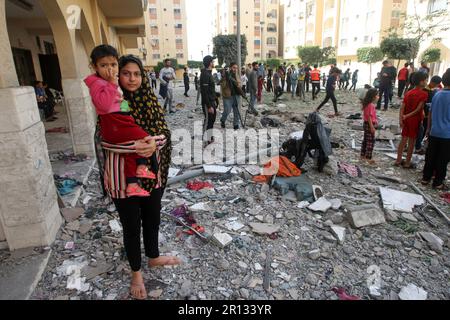 Les Palistins se promènaient au milieu de débris devant le bâtiment abritant le plat (dernier étage) d'un chef militaire du Jihad islamique, détruit par une attaque aérienne israélienne à Khan Yunis dans la bande de Gaza, à Thunsday 11 mai 2023. L'armée israélienne et les militants de Gaza ont échangé de lourds tirs transfrontaliers du jour au lendemain, avec au moins 25 Palestiniens tués sur deux jours. Photo par Ismael Mohamad/UPI crédit: UPI/Alay Live News Banque D'Images