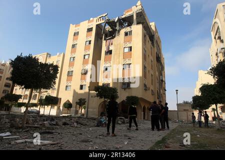 Les Palistins se promènaient au milieu de débris devant le bâtiment abritant le plat (dernier étage) d'un chef militaire du Jihad islamique, détruit par une attaque aérienne israélienne à Khan Yunis dans la bande de Gaza, à Thunsday 11 mai 2023. L'armée israélienne et les militants de Gaza ont échangé de lourds tirs transfrontaliers du jour au lendemain, avec au moins 25 Palestiniens tués sur deux jours. Photo par Ismael Mohamad/UPI crédit: UPI/Alay Live News Banque D'Images