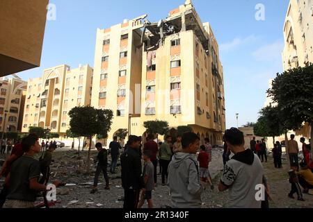 Les Palistins se promènaient au milieu de débris devant le bâtiment abritant le plat (dernier étage) d'un chef militaire du Jihad islamique, détruit par une attaque aérienne israélienne à Khan Yunis dans la bande de Gaza, à Thunsday 11 mai 2023. L'armée israélienne et les militants de Gaza ont échangé de lourds tirs transfrontaliers du jour au lendemain, avec au moins 25 Palestiniens tués sur deux jours. Photo par Ismael Mohamad/UPI crédit: UPI/Alay Live News Banque D'Images