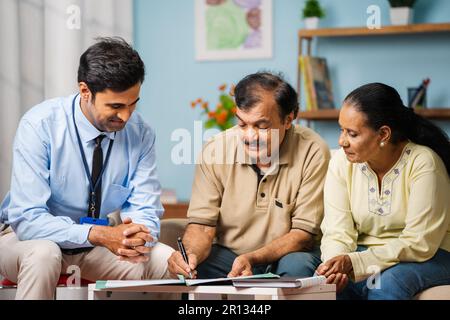 Banquier indien prenant signe de couple senior pour l'assurance ou les documents de prêt hypothécaire à la maison - concept de soutien financier, prestations de retraite et Banque D'Images
