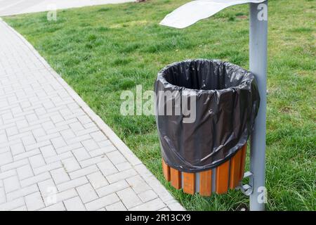 Une poubelle avec un sac à ordures est installée dans un endroit public, un parc. Situé à proximité du trottoir. Banque D'Images