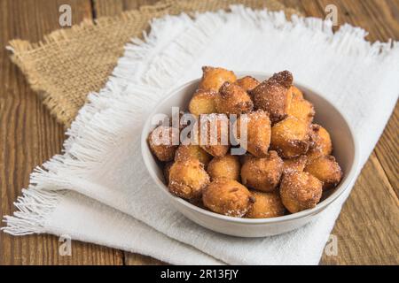 Castagnole maison, beignets typiques de carnaval italien avec sucre dans un bol blanc sur une table rustique en bois Banque D'Images