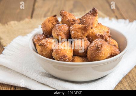 Castagnole maison, beignets typiques de carnaval italien avec sucre dans un bol blanc sur une table rustique en bois Banque D'Images